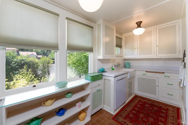 kitchen with white dishwasher, backsplash, sink, and white cabinets