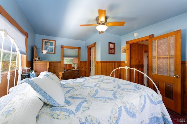 bedroom with ceiling fan and wooden walls