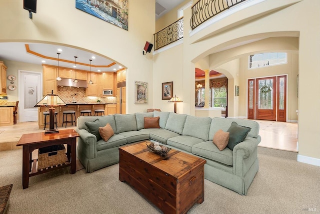 carpeted living room featuring a towering ceiling and a premium fireplace