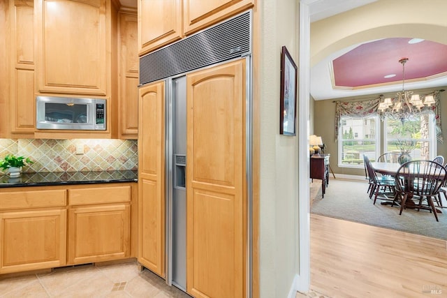 kitchen with appliances with stainless steel finishes, light tile patterned floors, decorative backsplash, and dark stone counters