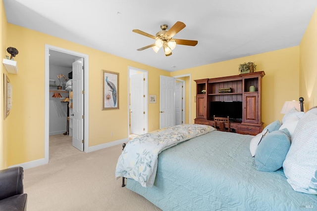 bedroom with a spacious closet, light colored carpet, and ceiling fan