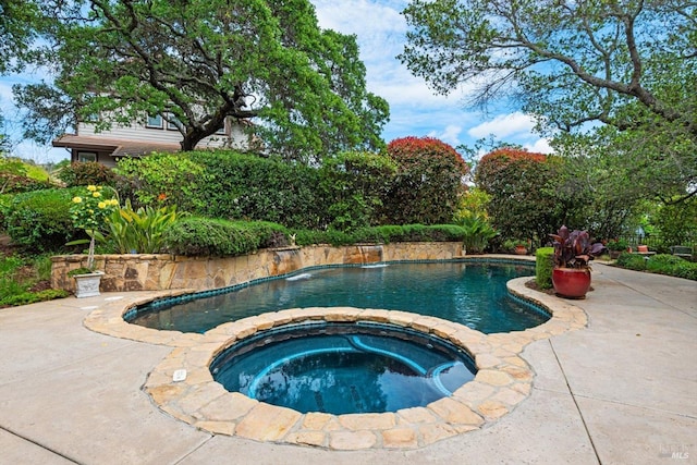 view of pool with a patio, pool water feature, and an in ground hot tub