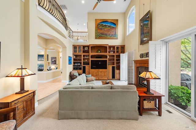 living room featuring a raised ceiling, light hardwood / wood-style floors, and ornate columns