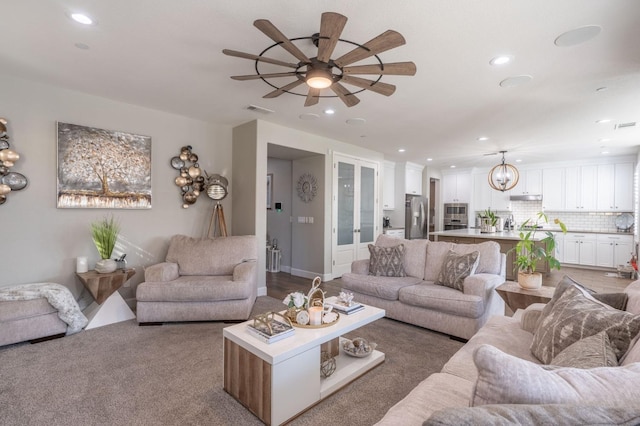 living room with ceiling fan with notable chandelier, recessed lighting, and visible vents