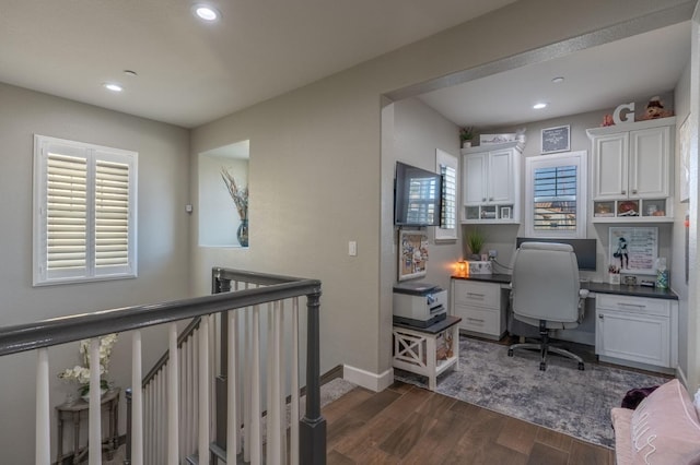 home office with built in desk, dark wood-type flooring, and a healthy amount of sunlight