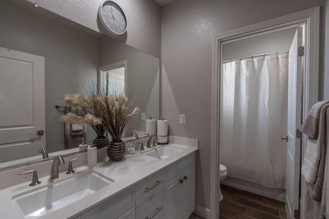 bathroom featuring double vanity, a sink, toilet, and wood tiled floor