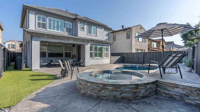 back of house featuring an in ground hot tub, a patio area, a fenced backyard, a yard, and stucco siding