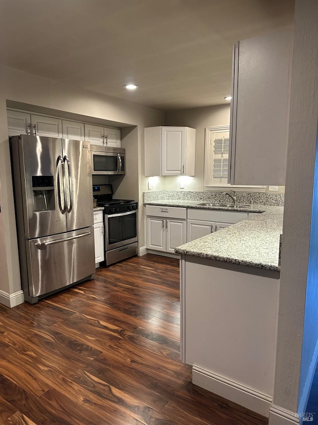 kitchen with dark wood-type flooring, sink, stainless steel appliances, light stone countertops, and white cabinets