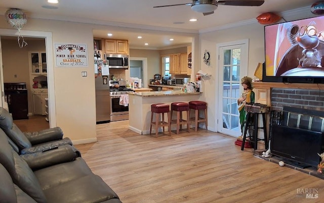 living room featuring a brick fireplace, crown molding, ceiling fan, and light wood-type flooring