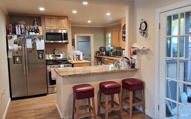 kitchen with light stone counters, stainless steel appliances, kitchen peninsula, and light brown cabinets