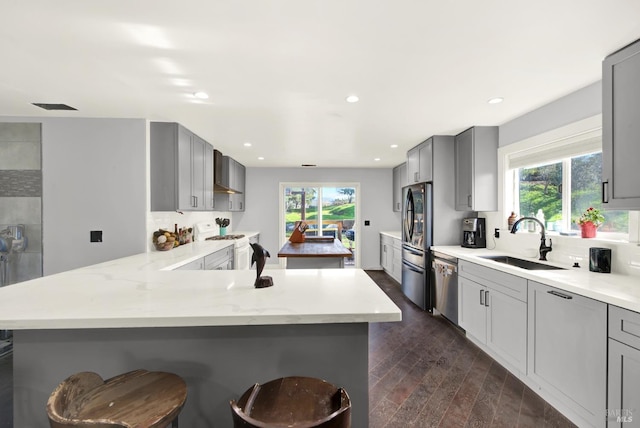 kitchen with stainless steel appliances, sink, a breakfast bar, and gray cabinets