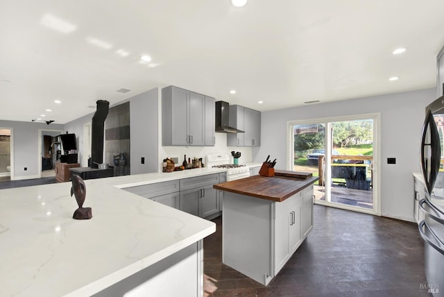 kitchen with a kitchen island, white gas range, butcher block counters, gray cabinetry, and wall chimney range hood