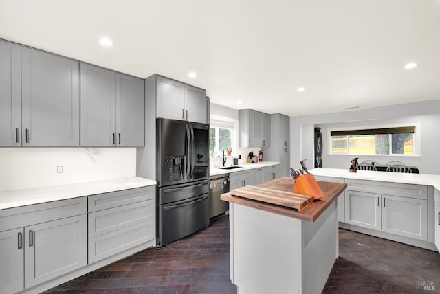 kitchen with butcher block counters, sink, dark hardwood / wood-style floors, gray cabinets, and stainless steel appliances