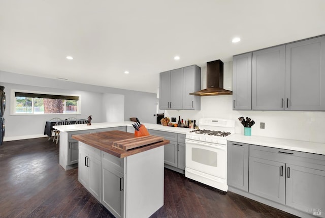 kitchen featuring white gas range, butcher block counters, gray cabinetry, and wall chimney exhaust hood