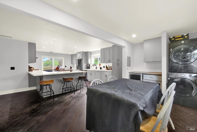 dining space with stacked washer and dryer, sink, and dark hardwood / wood-style floors