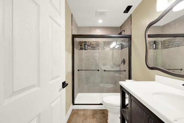 bathroom with vanity, a shower with shower door, hardwood / wood-style floors, and toilet