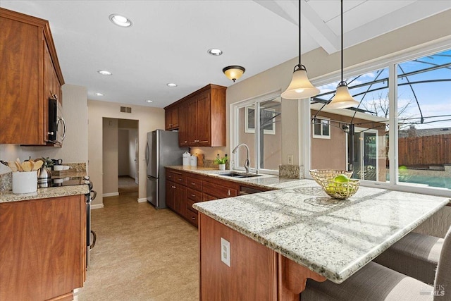 kitchen featuring a kitchen bar, sink, decorative light fixtures, kitchen peninsula, and stainless steel appliances