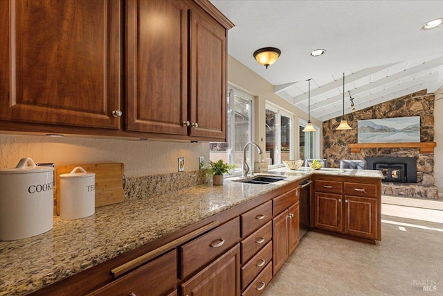 kitchen featuring a fireplace, lofted ceiling, sink, kitchen peninsula, and light stone countertops