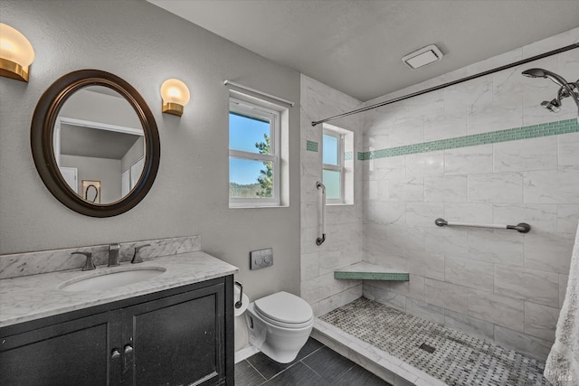 bathroom featuring vanity, tiled shower, tile patterned floors, and toilet