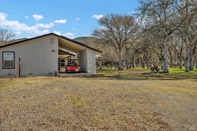 view of side of home with a mountain view and a lawn