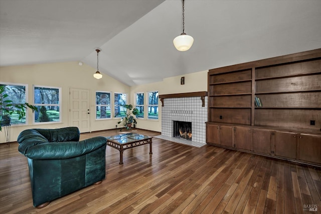 living room with dark hardwood / wood-style flooring, vaulted ceiling, and a tile fireplace