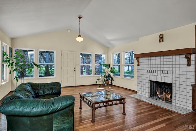 living room featuring wood-type flooring, a tile fireplace, and vaulted ceiling