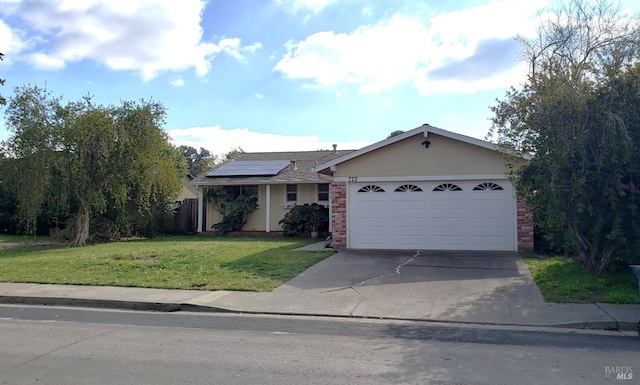 ranch-style house with driveway, solar panels, an attached garage, a front yard, and brick siding