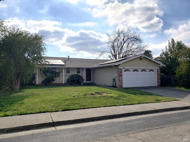 single story home featuring a garage, brick siding, driveway, roof mounted solar panels, and a front lawn