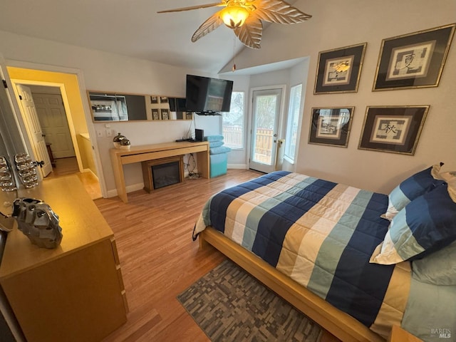 bedroom featuring vaulted ceiling, a fireplace, access to outside, ceiling fan, and light hardwood / wood-style floors