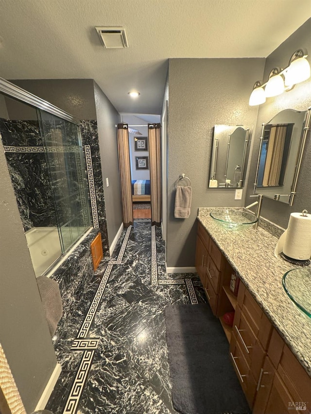 bathroom featuring vanity, a shower with door, and a textured ceiling