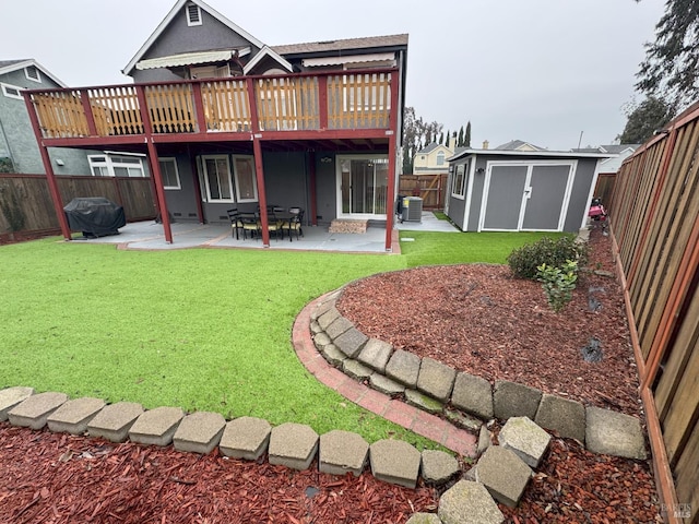 rear view of property featuring a wooden deck, a yard, a patio area, and a storage unit