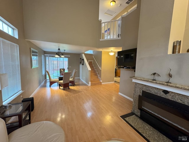 living room with an inviting chandelier, a towering ceiling, and light hardwood / wood-style flooring