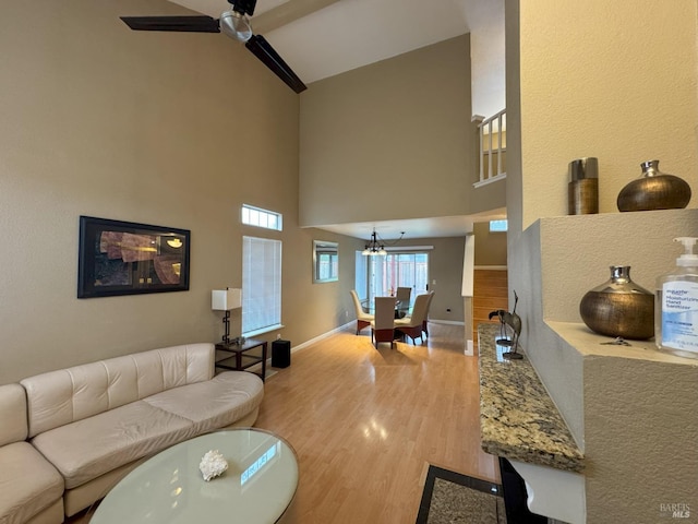 living room with a high ceiling, wood-type flooring, and ceiling fan with notable chandelier