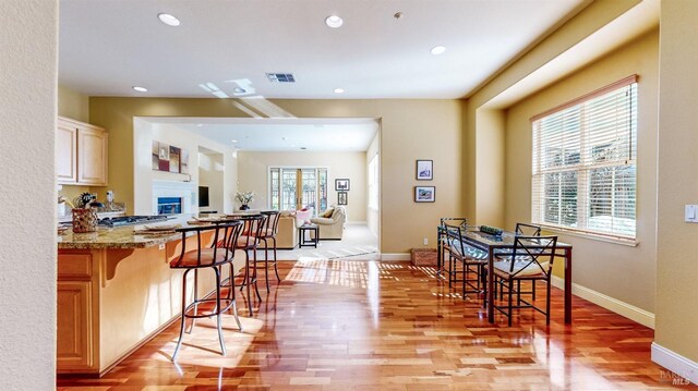 kitchen with light hardwood / wood-style flooring, light stone countertops, and a kitchen bar