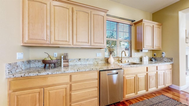 kitchen with hardwood / wood-style floors, light brown cabinetry, sink, stainless steel dishwasher, and light stone counters