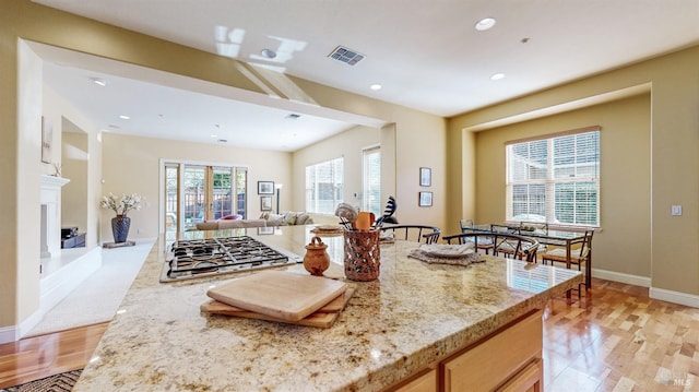 kitchen with light stone counters, stainless steel gas cooktop, recessed lighting, visible vents, and open floor plan