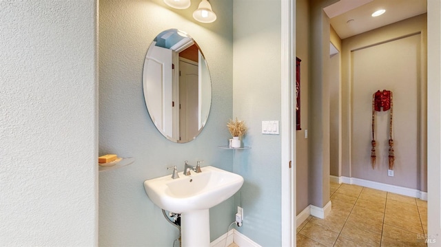 bathroom with tile patterned flooring, baseboards, and a sink