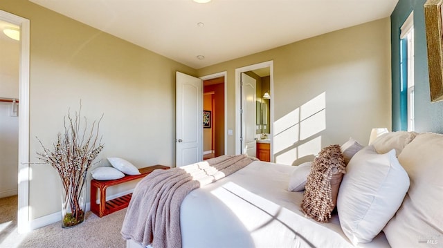 bedroom with connected bathroom and light colored carpet