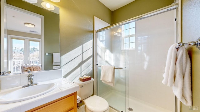 bathroom with vanity, toilet, and a shower with door