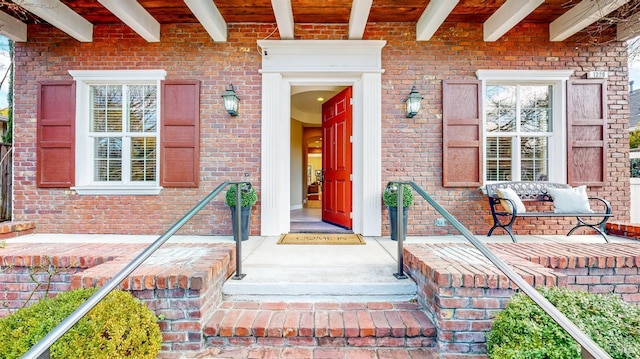 entrance to property featuring covered porch and brick siding