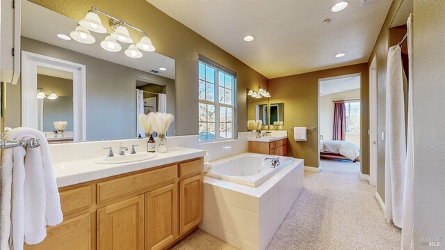 bathroom with vanity, plenty of natural light, and tiled bath