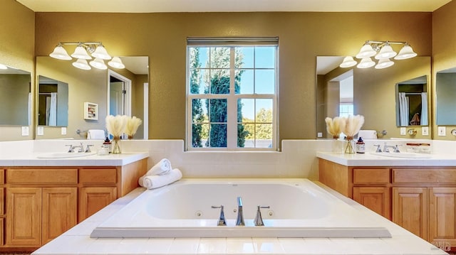 bathroom with two vanities, a sink, and a tub with jets