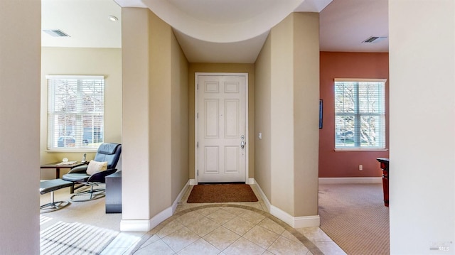 entryway featuring visible vents, baseboards, light colored carpet, and light tile patterned flooring