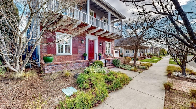 view of front of house featuring brick siding and a balcony