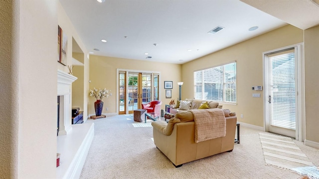 living room with light colored carpet, visible vents, baseboards, french doors, and a glass covered fireplace