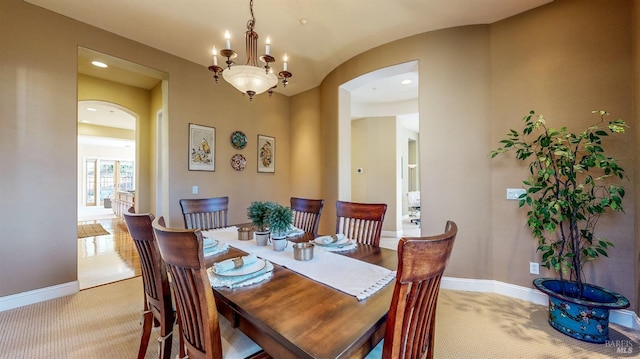 dining area featuring light colored carpet, arched walkways, and baseboards