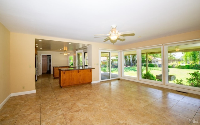 kitchen with light tile patterned floors, stainless steel fridge, ceiling fan, and kitchen peninsula