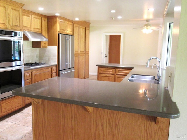 kitchen featuring sink, a kitchen bar, decorative backsplash, kitchen peninsula, and stainless steel appliances