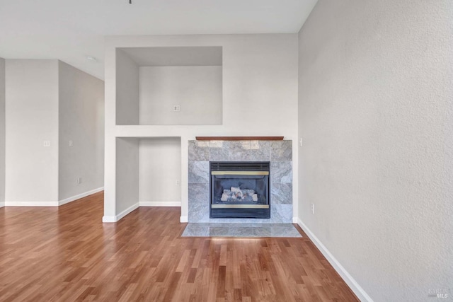 unfurnished living room featuring a tiled fireplace and hardwood / wood-style flooring