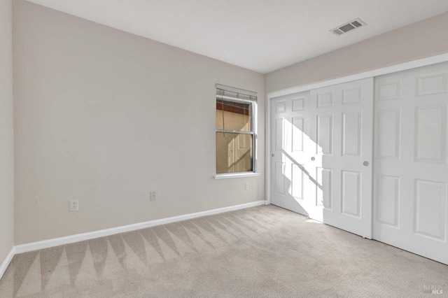 unfurnished bedroom featuring light colored carpet and a closet